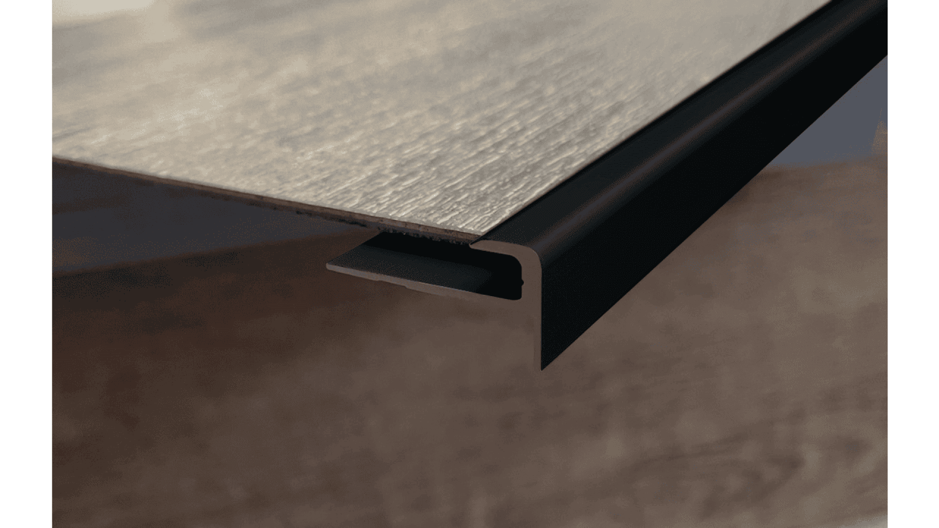 A close-up view of a wood panel edge with a black L-shaped trim or edging attached, illustrating the corner detail and joinery.