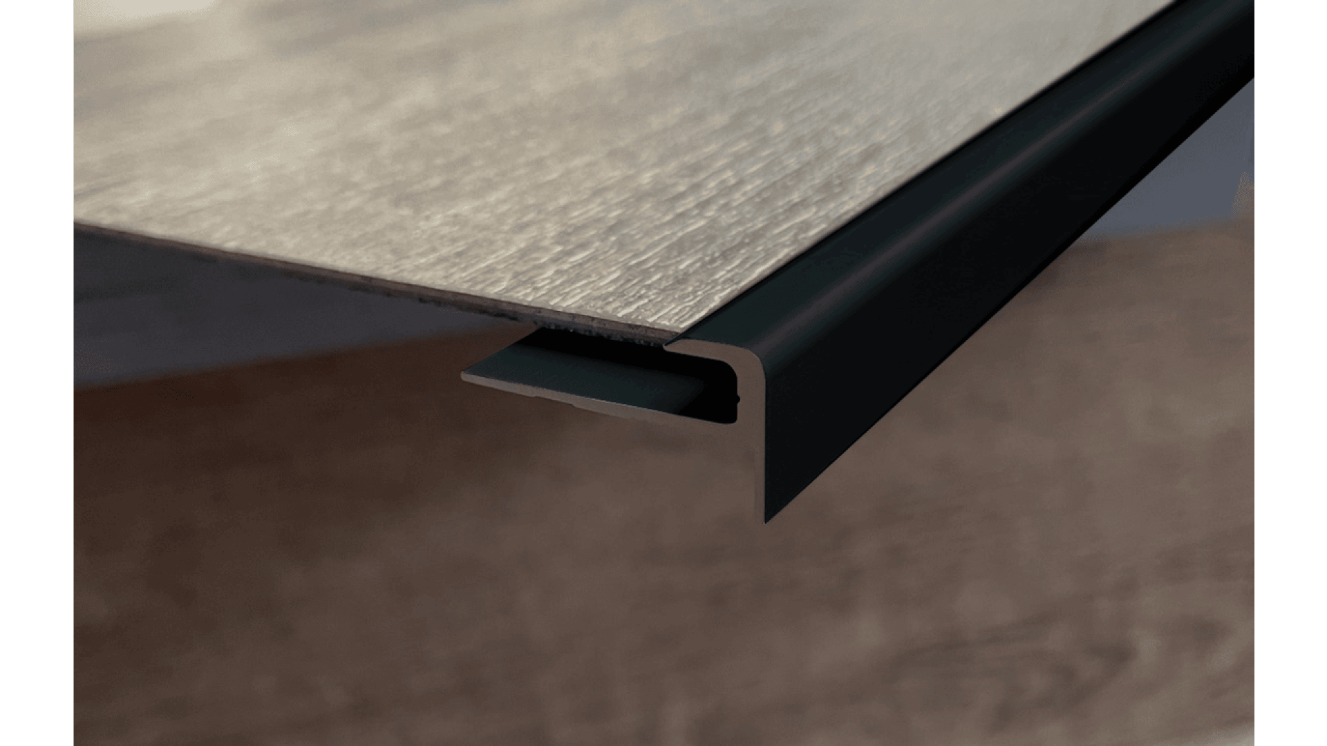 Nahaufnahme einer Vinyl-Bodendiele mit einer dunkel gefärbten Treppenkantenleiste an der Kante, die die Installation eines Treppenbodens veranschaulicht.