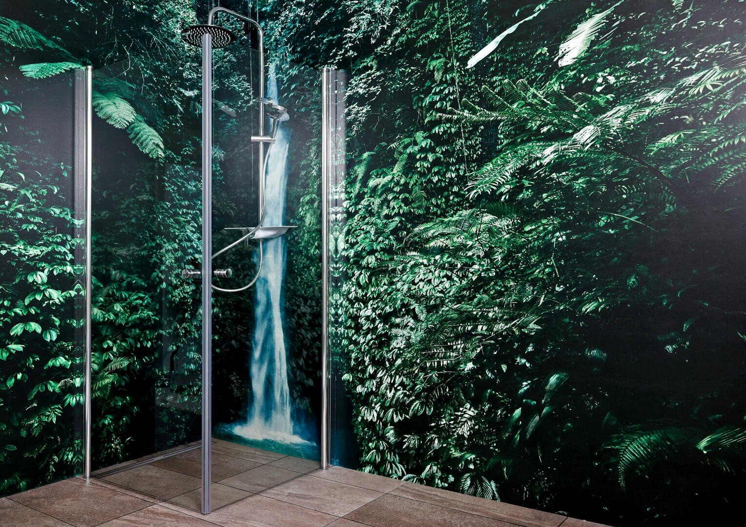 Eine moderne Dusche mit Glasplatten ist an einer Wand installiert, an der ein Wandgemälde mit einem üppigen grünen Wald und einem Wasserfall zu sehen ist, wodurch die Illusion entsteht, dass sich die Dusche in einem Dschungel befindet.