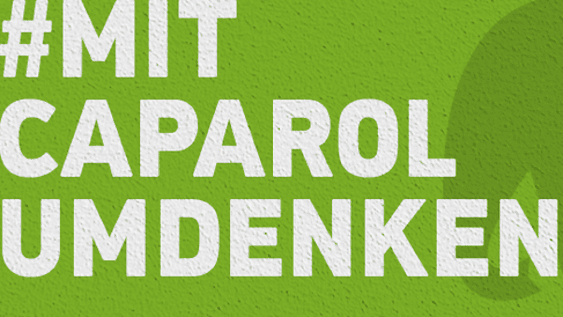 White text on a textured green background reads #MIT CAPAROL UMDENKEN. A partial green leaf shape is visible on the right side.