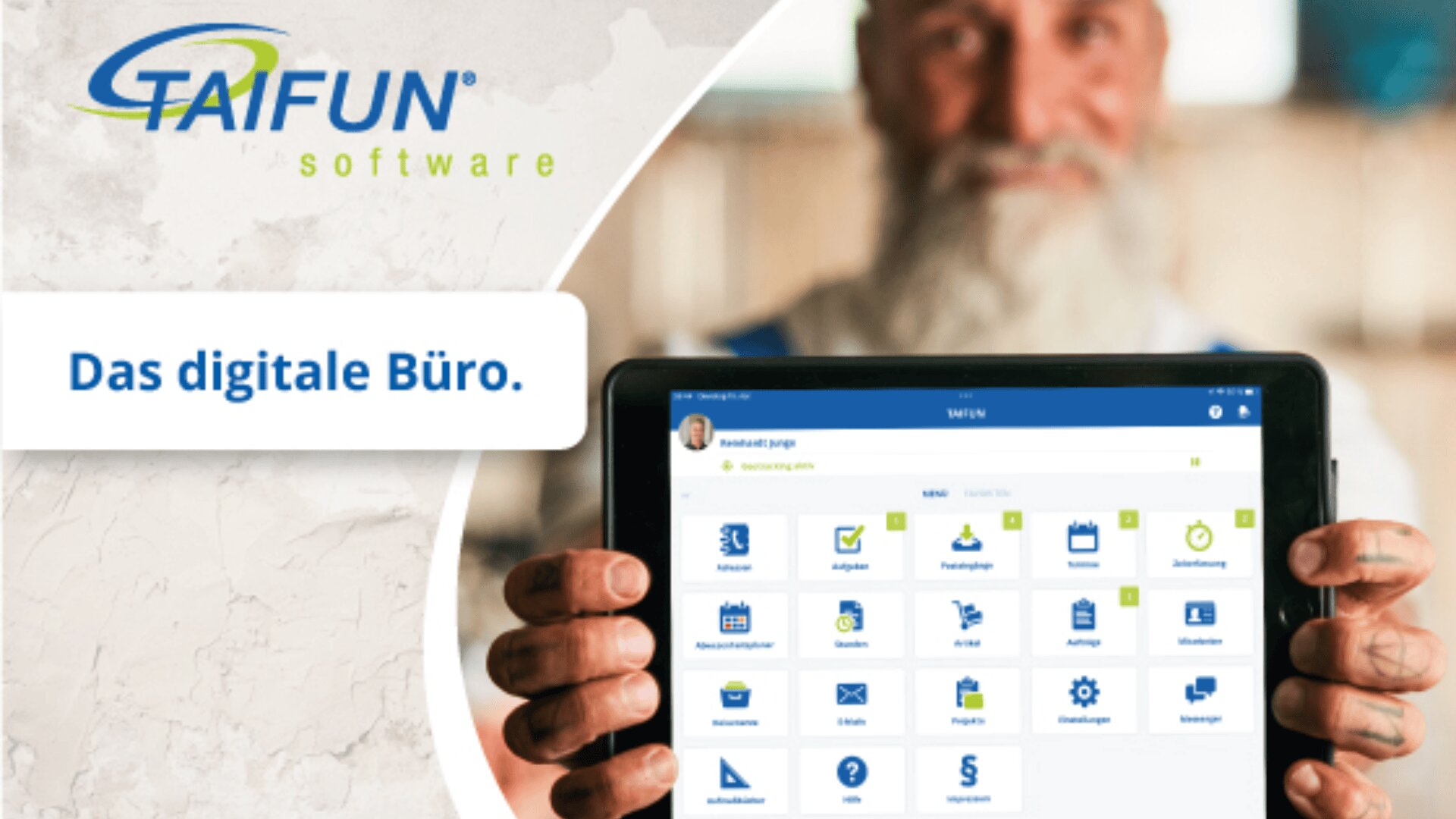Ein lächelnder Mann mit Bart hält ein Tablet mit einer Softwareoberfläche und verschiedenen App-Symbolen in der Hand. Links steht „Das digitale Büro“. Oben links befindet sich die TAIFUN-Software.