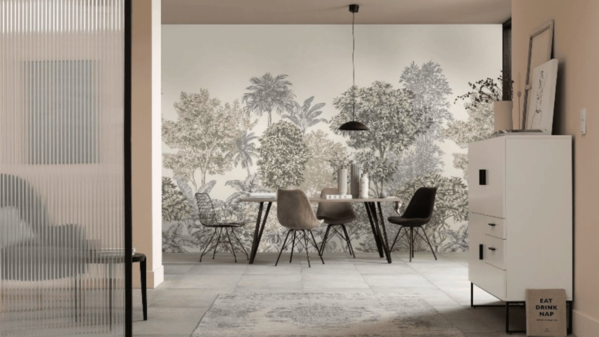 Moderner Essbereich mit einem Tisch und vier Stühlen vor einer Wand mit einem botanischen Wandgemälde, das Bäume und Laub darstellt. Die minimalistische Einrichtung umfasst eine Hängeleuchte und einen weißen Schrank.