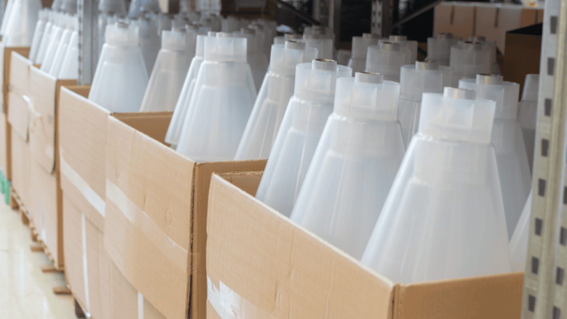 Several large cardboard boxes are filled with stacked white plastic cones or lampshades, placed on metal shelves in a storage or warehouse setting.