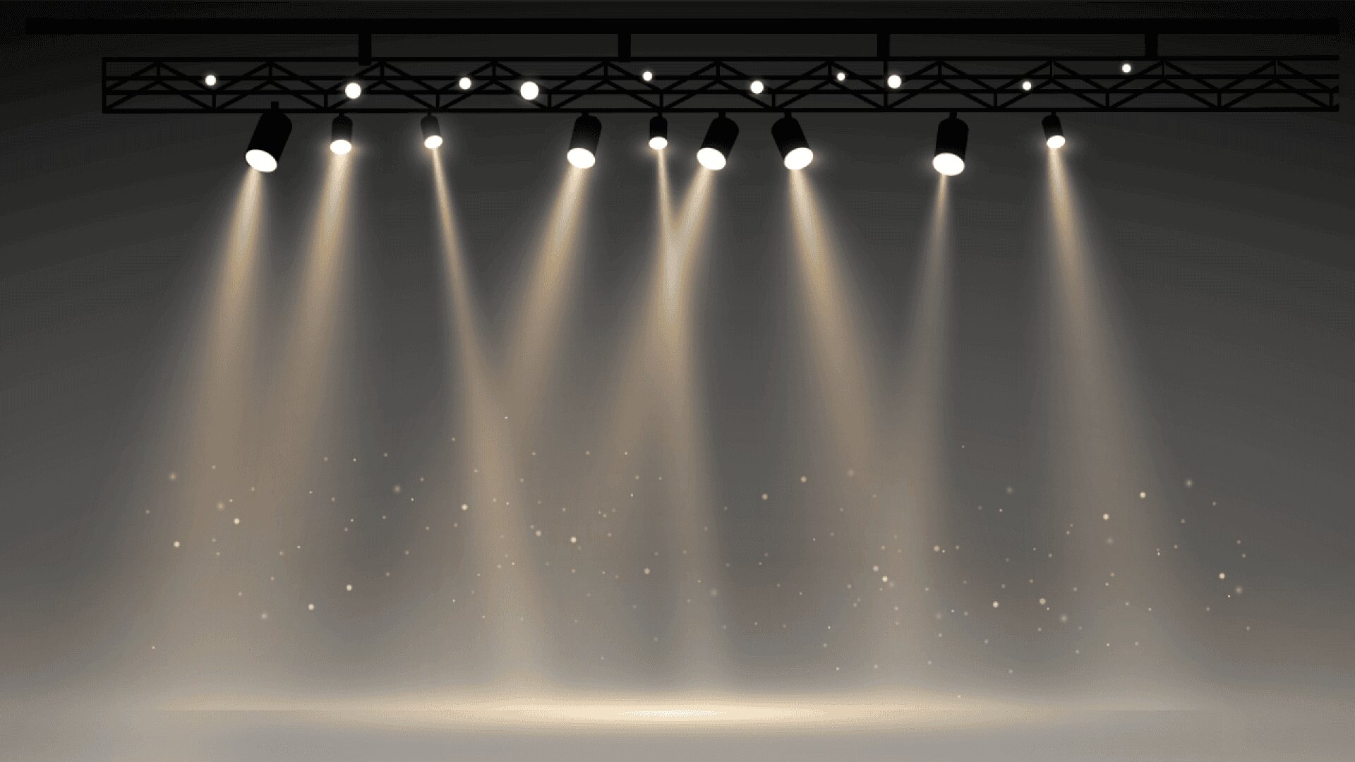 A row of stage spotlights shines down from a metal truss onto a dark, empty stage, creating beams of light and subtle sparkles in the misty air.