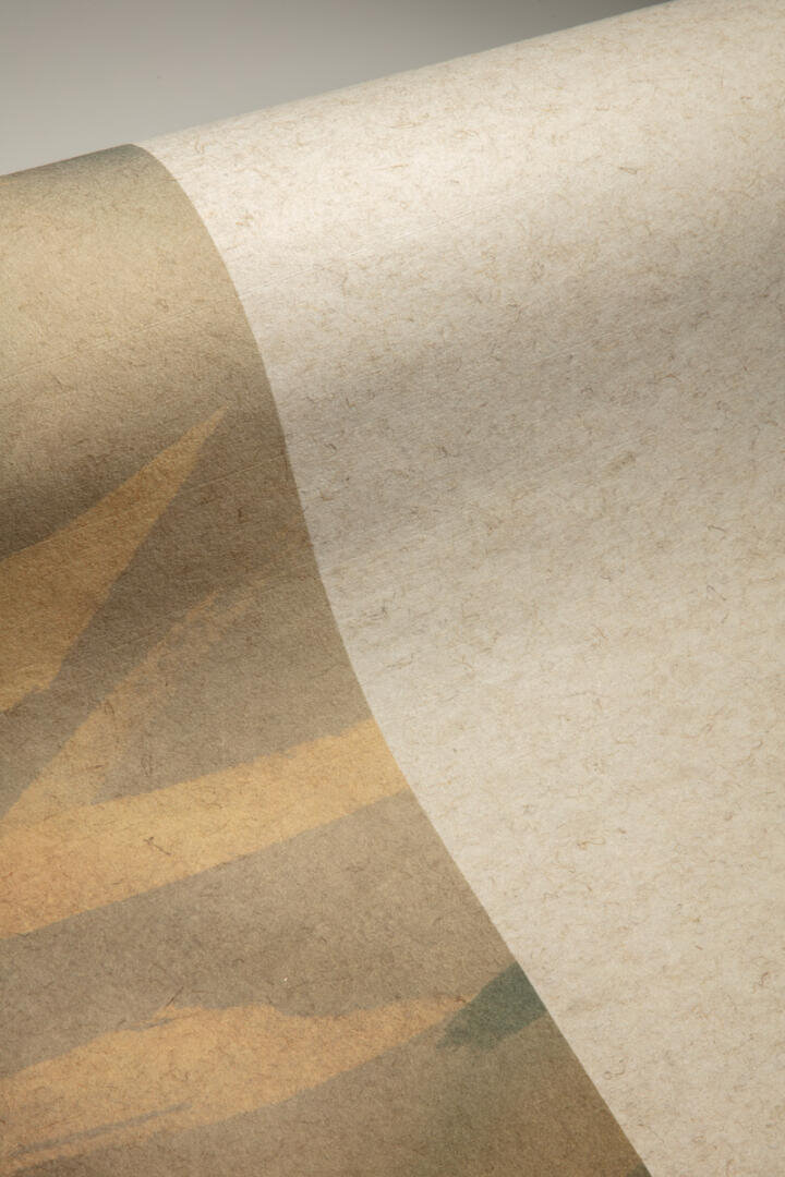 Nahaufnahme eines Blattes strukturierten, beigen Papiers mit einem schwachen, abstrakten Muster in gedämpften Braun- und Gelbtönen entlang einer Kante. Das Papier ist teilweise gerollt, wodurch eine sanfte Kurve und ein subtiler Schatten entstehen.